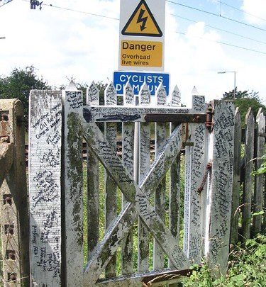 The old track over the Downs, crossing the rails by the former station, is still there, guarded by signs 'STOP', 'LOOK', 'LISTEN' and what must be the most literary railway crossing gate anywhere. A storybook, it ought to be preserved with its odd graffiti comments, its gossip and world-encompassing sentiments: 'Chris Griggs cried over Biafra', reveals one of the statements. | Dave Bullock