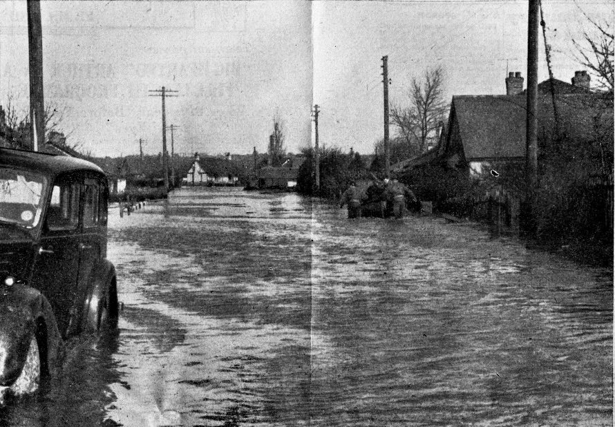 This flooded Canvey street is typical of the scenes throughout the Island on Sunday morning, when general evacuation was ordered. The water has now gone down considerably in depth and the breaches in the sea wall have been repaired. Nearly the entire Island population of 12,000 people were evacuated, and it will be some time before they are allowed to return to their homes, many of which can almost be entirely written off. Morale of the Islanders is still high, as witness the chalked notice outside an Island store, 
