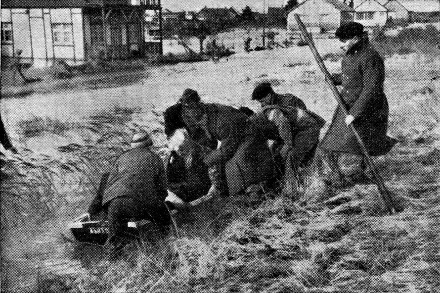 Willing hands lower an old lady into a rowing boat after she had been rescued from her flooded home at Canvey.