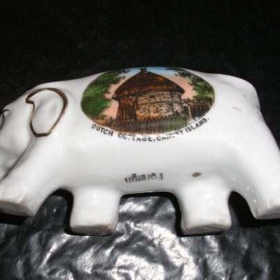 Porcelain Elephant with picture of Dutch cottage Canvey Island with lettering of same. Length is 3.5inch and height from 1.5 - 2inches To base the wording Foreign | Carol Rowles