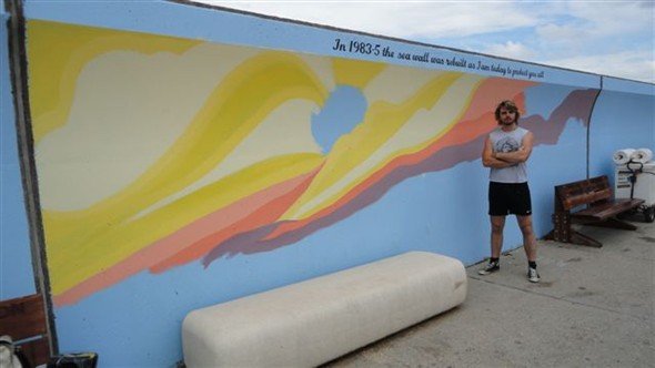 Darren Jones beside his mural on the seawall. | Janet Penn
